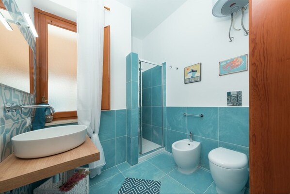 Une salle de bain avec un lavabo blanc, une douche, un bidet et des toilettes.