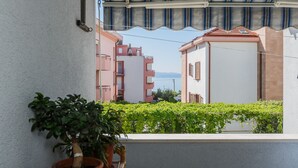 A balcony with a potted plant, a view of neighboring buildings, and a retractable awning. - Apartments Zenta (Split)
