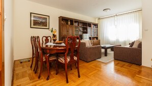 A living room with a wooden dining table, chairs, a sofa, and a bookshelf. - Apartments Zenta (Split)