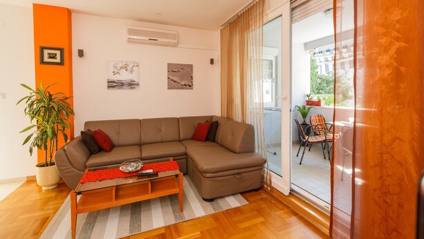 A modern living room with a sectional sofa, a coffee table, and a potted plant. - Apartments Zenta (Split)
