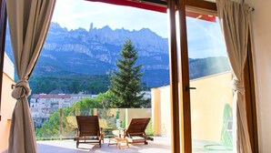 Un balcon avec deux chaises en bois, une table et une vue sur les montagnes.