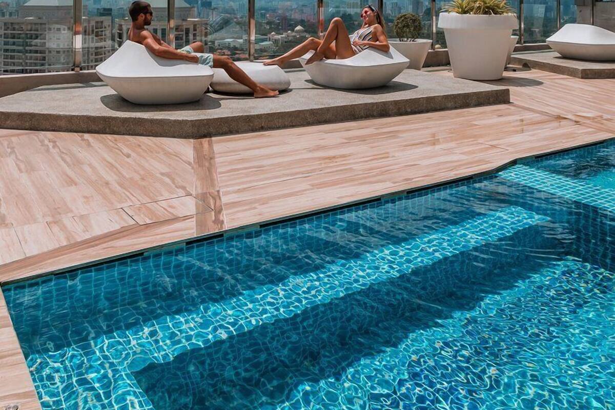 A rooftop pool area with lounge chairs and a view of the city skyline.