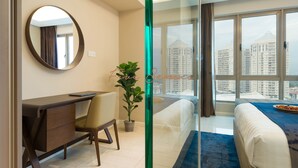 Una habitación de hotel moderna con escritorio, silla y un amplio ventanal con vistas a la ciudad.