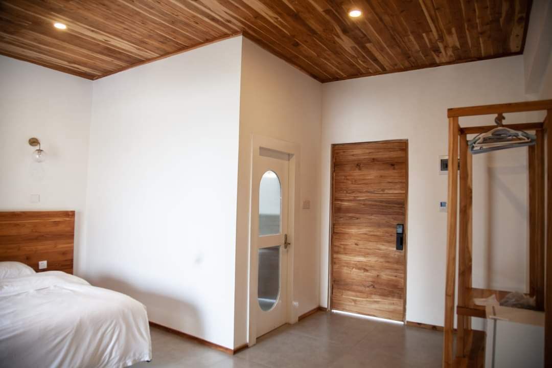 Een slaapkamer met een houten hoofdeinde, een bed, een houten deur en een houten garderobe.