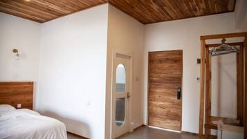 Een slaapkamer met een houten hoofdeinde, een bed, een houten deur en een houten garderobe.