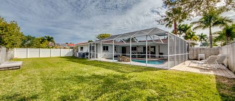 A house with a covered patio, a swimming pool, and a fenced backyard.