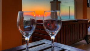Two empty wine glasses on a wooden table with a sunset view through a window.