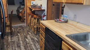Eine Küche mit Holzschränken, einem Geschirrspüler und einem Barhocker.