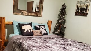 Ein Schlafzimmer mit einem Bettgestell aus Holz, einem Spiegel mit rustikalem Rahmen und einer Wand mit Bär-Motiv.