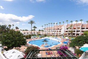 A hotel with a central swimming pool surrounded by palm trees and sun loungers. - Parque Santiago II 85 - Two Bed south facing (Playa de la Américas)