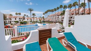 A resort with multiple white buildings, a swimming pool, and palm trees. - Parque Santiago II 85 - Two Bed south facing (Playa de la Américas)