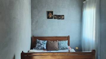 A bedroom with a wooden bed, a gray wall, and a ceiling with wooden panels.