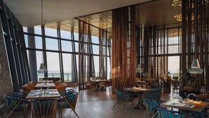 A restaurant with high ceilings, large windows, and modern decor. Tables are set with chairs, and there are hanging lights. - Renaissance Xiamen Hotel (Xiamen)