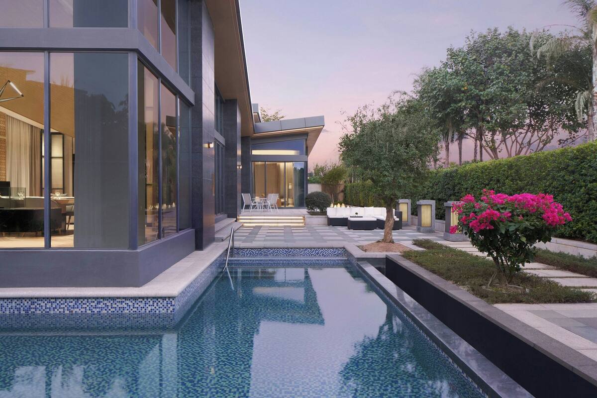A modern house with a swimming pool, outdoor seating, and a garden.