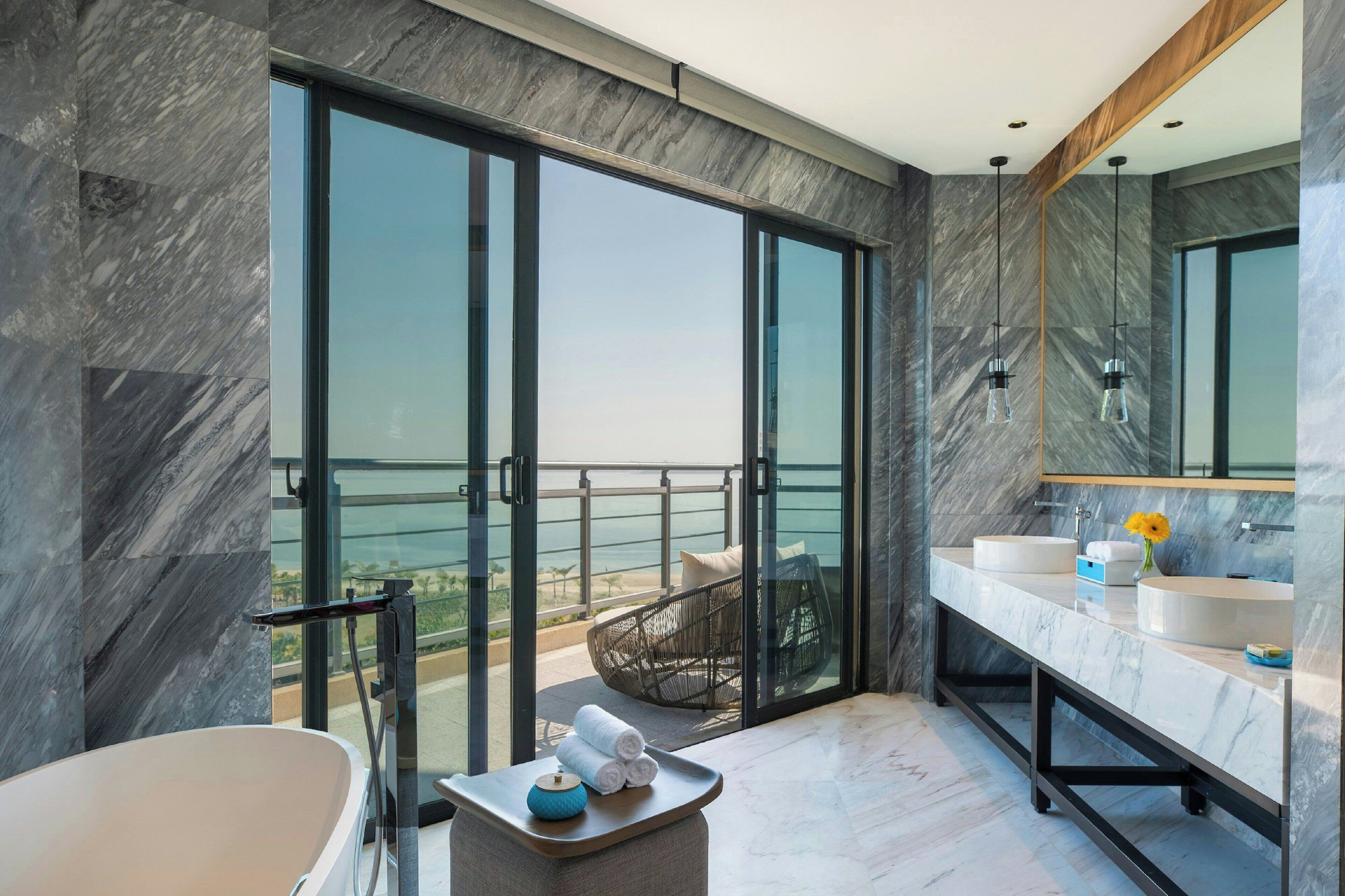 Un bagno moderno con vasca, due lavandini e un grande specchio. Dispone di un balcone con vista sull'oceano.