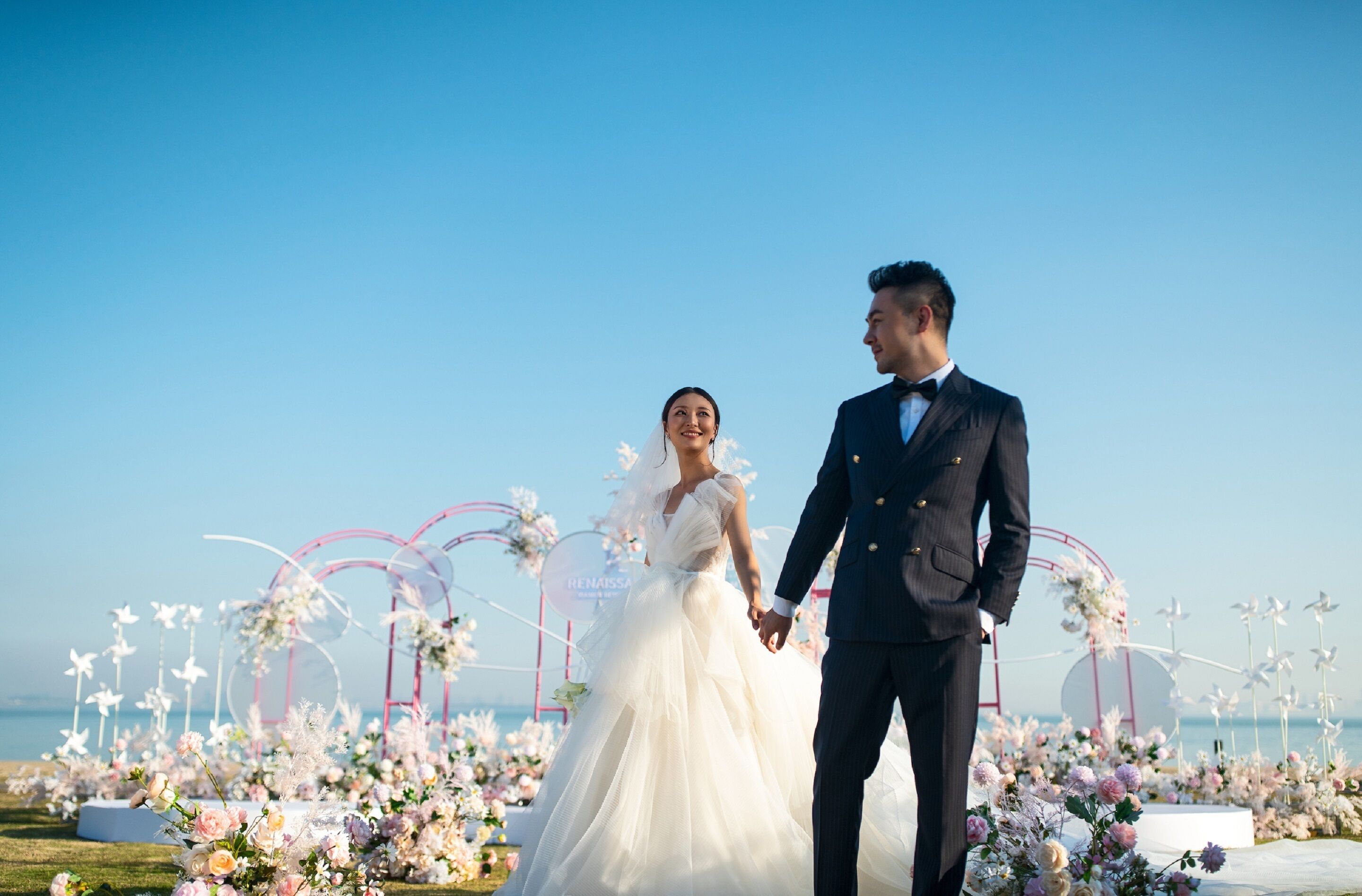 Une cérémonie de mariage sur une plage, agrémentée de décorations florales et se déroulant sous un ciel dégagé.