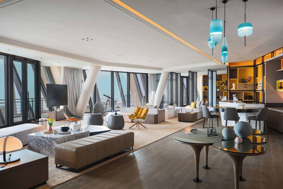 A modern living room with a sofa, coffee table, and a dining area with a round table and chairs.
