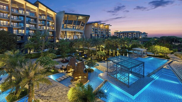 A modern hotel with multiple floors, a swimming pool, and surrounding greenery. - Renaissance Xiamen Hotel (Xiamen)
