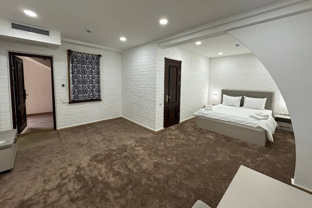 A bedroom with a large bed, a wardrobe, and a door leading to another room.