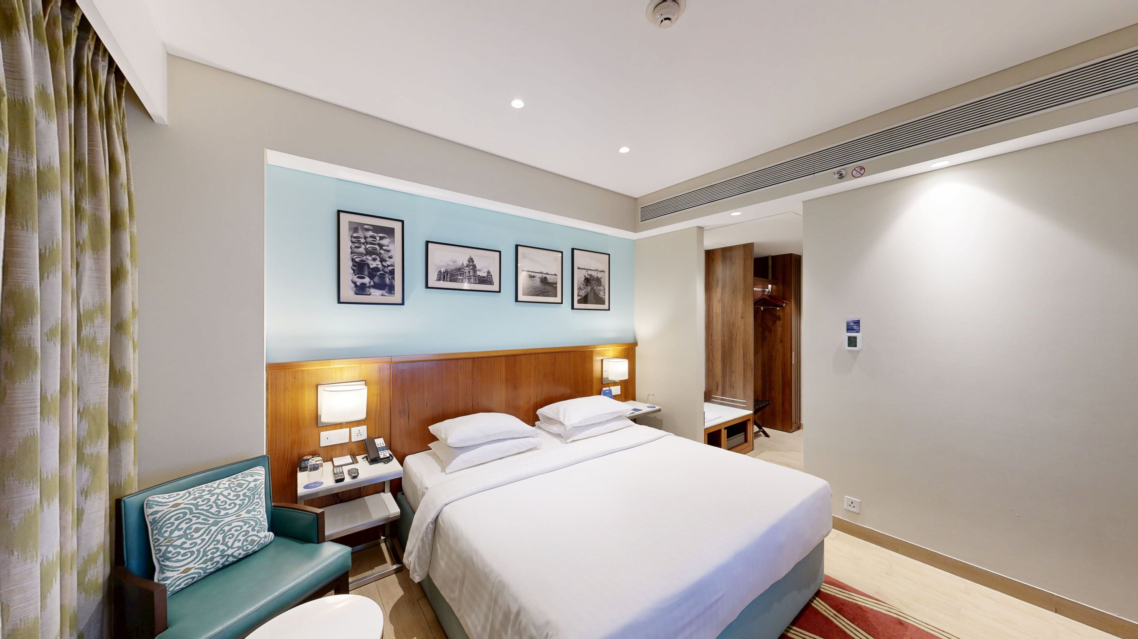 Una habitación de hotel con cama, mesita de noche, lámpara y una silla.