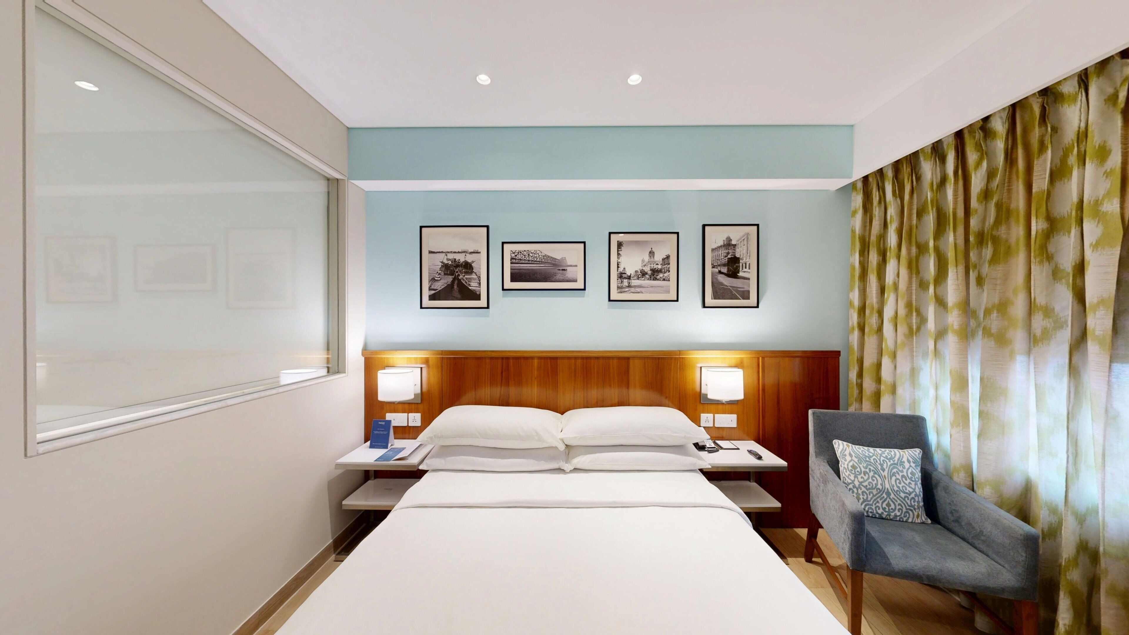 Ein Hotelzimmer mit einem großen Bett, zwei Nachttischen, einem Sessel und Wandleuchten.