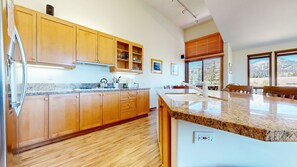 A kitchen with wooden cabinets, granite countertops, and a built-in island with a sink. - Snowcreek V 999 Mammoth Mountain Views, Private Washer Dryer, Pet-Friendly by RedAwning (Mammoth Lakes)
