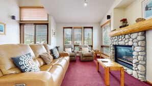 A cozy living room with a leather sofa, armchairs, a fireplace, and large windows. - Snowcreek V 999 Mammoth Mountain Views, Private Washer Dryer, Pet-Friendly by RedAwning (Mammoth Lakes)