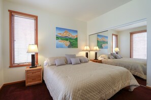 Two large beds with matching headboards, a wooden nightstand, and a small table complete this cozy retreat.