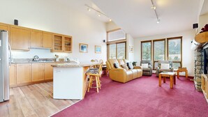 A spacious living area with a kitchen, a fireplace, and large windows. - Snowcreek V 999 Mammoth Mountain Views, Private Washer Dryer, Pet-Friendly by RedAwning (Mammoth Lakes)