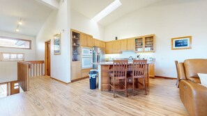 A spacious kitchen with wooden cabinets, a dining area with a table and chairs, and a large window providing natural light. - Snowcreek V 999 Mammoth Mountain Views, Private Washer Dryer, Pet-Friendly by RedAwning (Mammoth Lakes)