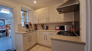A compact kitchen with white cabinets, a gas stove, and a microwave.