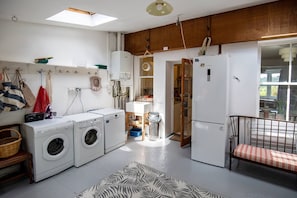 A compact kitchen with a washing machine, a refrigerator, and a dining area with a bench.