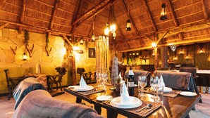 Een restaurant met houten tafels en stoelen, stenen muren en hangende lantaarns.