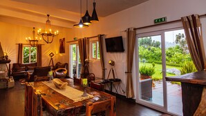 Een ruime kamer met een houten eettafel, lederen zitplaatsen en een groot raam met uitzicht op groen.