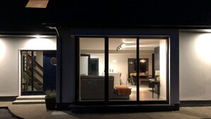 Una casa moderna con un ventanal de vidrio que da a una sala de estar, una escalera y un comedor.
