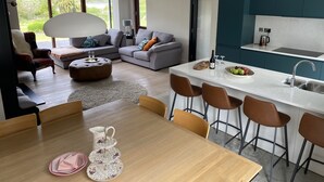 Una cocina moderna con encimera blanca, un lavamanos y una zona de comedor con mesa y sillas de madera.