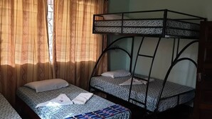 Um quarto com duas beliches, uma janela com cortinas e um guarda-roupa de madeira.