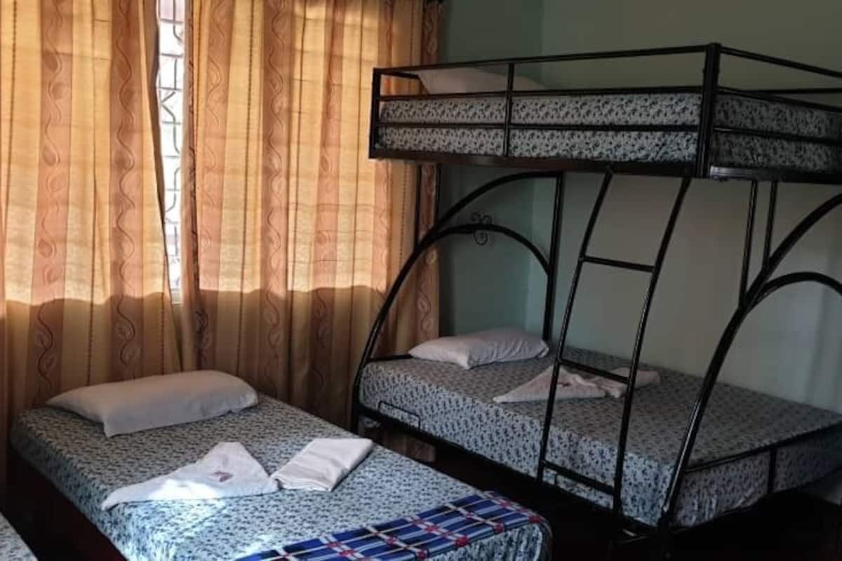 A room with two bunk beds, a window with curtains, and a wooden wardrobe.