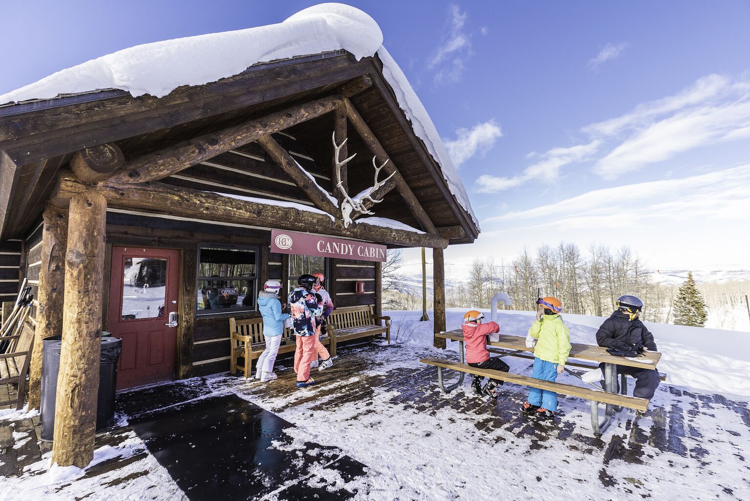 A wooden cabin with a sign reading "Candy Cabin" and a bench outside.