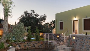 A stone staircase leading to a building with a green facade and two doors, surrounded by trees and a small garden. - Mela Villas (Rethymno)