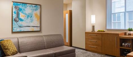 Una sala de estar moderna con un sofá, un reposapiés y un cuadro en la pared.