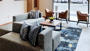 A modern lobby with a grey sofa, wooden accents, and a large window offering a view of the street. - Hyatt Place Houston Downtown (Houston)