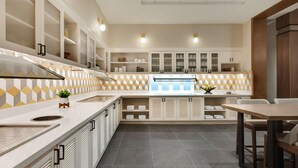 A modern kitchen with white cabinets, a central island, and a dining area with a wooden table and chairs. - Hyatt Place Houston Downtown (Houston)