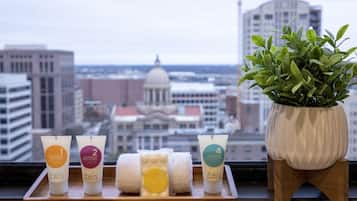 A tray with four skincare products and a potted plant on a windowsill with a cityscape view.