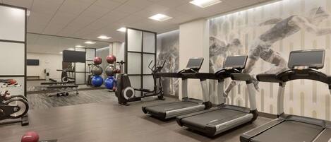 Ett gym med löpband, träningsbollar och en vägg täckt med speglar.