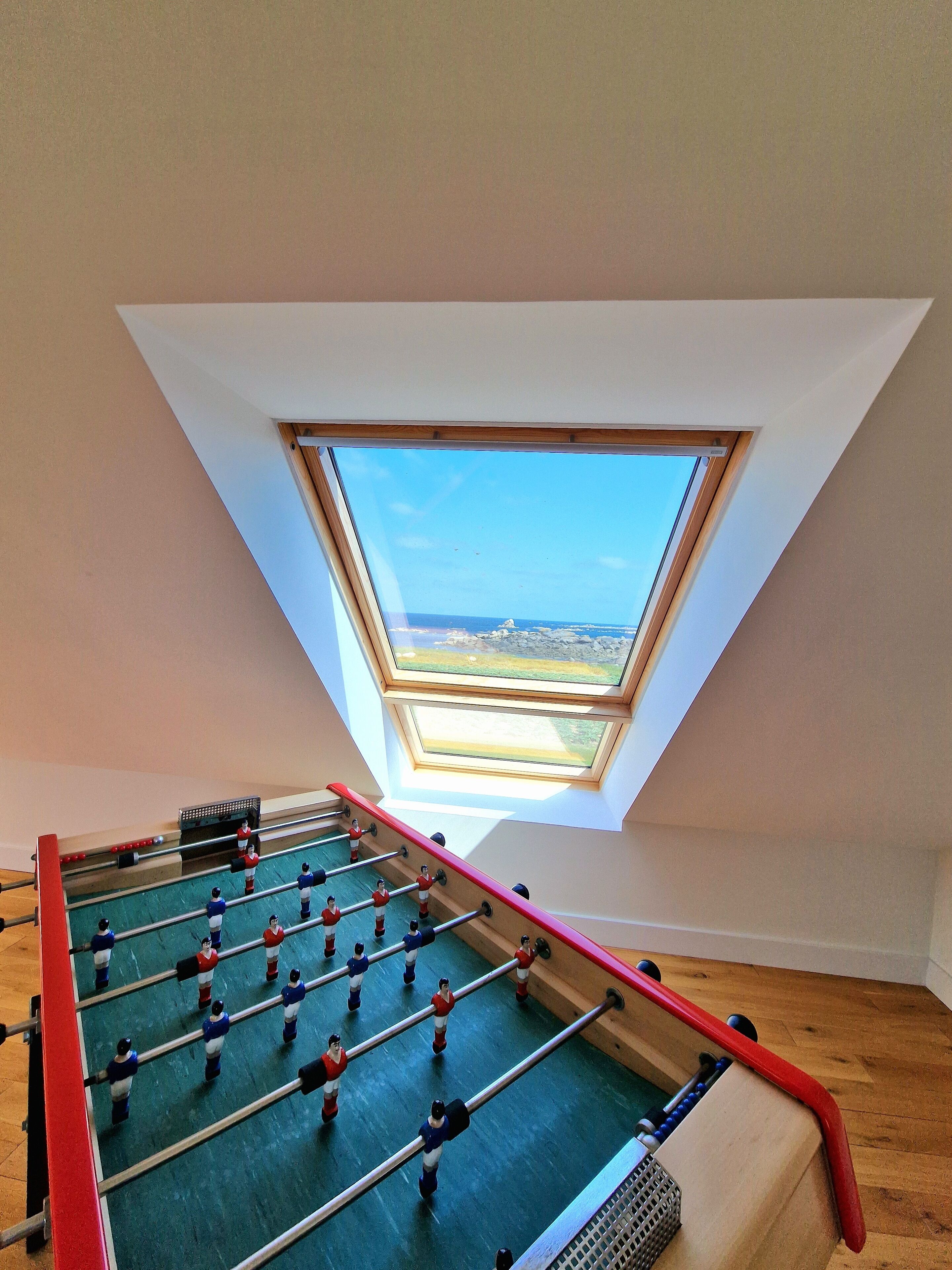 A foosball table in a room with a sloped ceiling and a skylight.