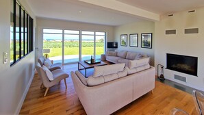A spacious living room with a large sectional sofa, a flat-screen TV, and a fireplace. - Villa Frouden, Beach, sea view, jacuzzi (Plouescat)
