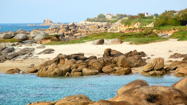 A rocky beach with large boulders, a sandy shore, and a building in the background. - Villa Frouden, Beach, sea view, jacuzzi (Plouescat)