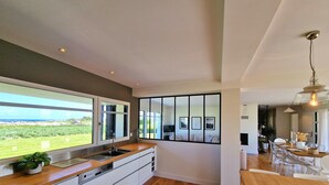 A modern kitchen with a large window, wooden flooring, and a view of the outdoors. - Villa Frouden, Beach, sea view, jacuzzi (Plouescat)