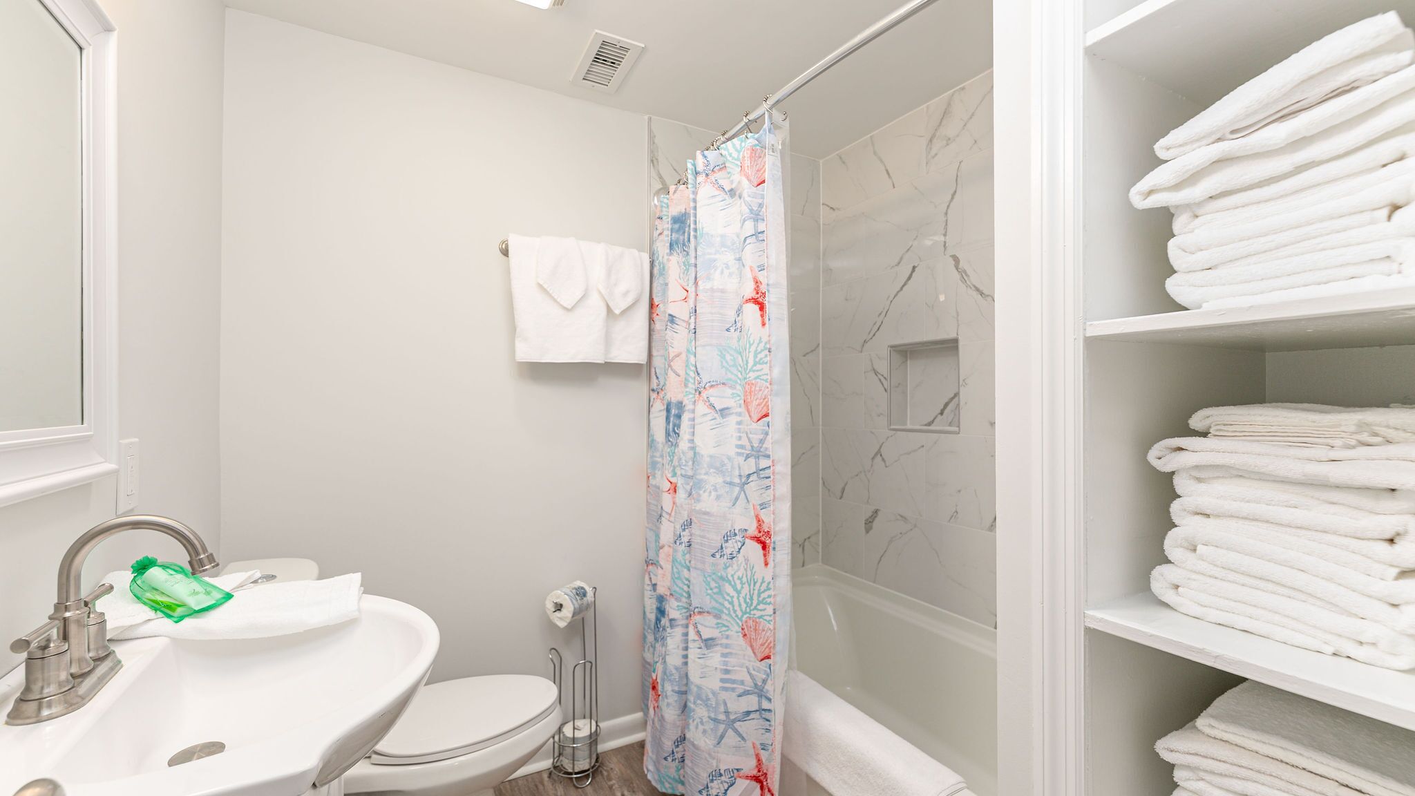 Une salle de bain équipée d’un lavabo, de toilettes, d’une douche et d’un porte-serviettes avec des serviettes pliées.